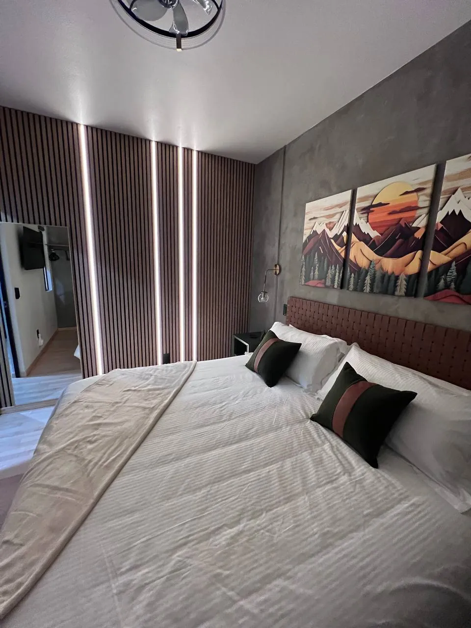 Bedroom with mountain mural art over a slat headboard wall