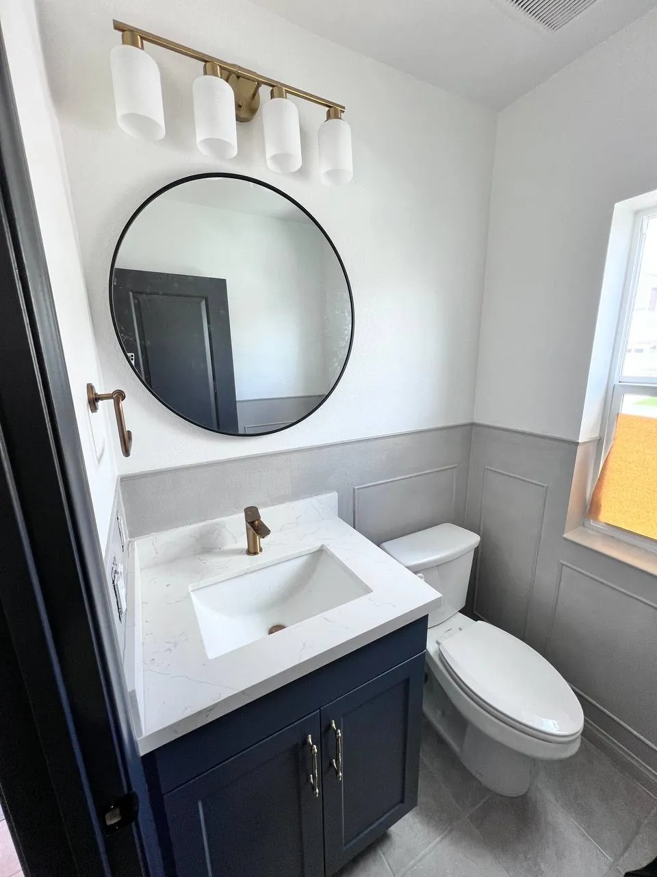 Bathroom vanity with round mirror and dark cabinet