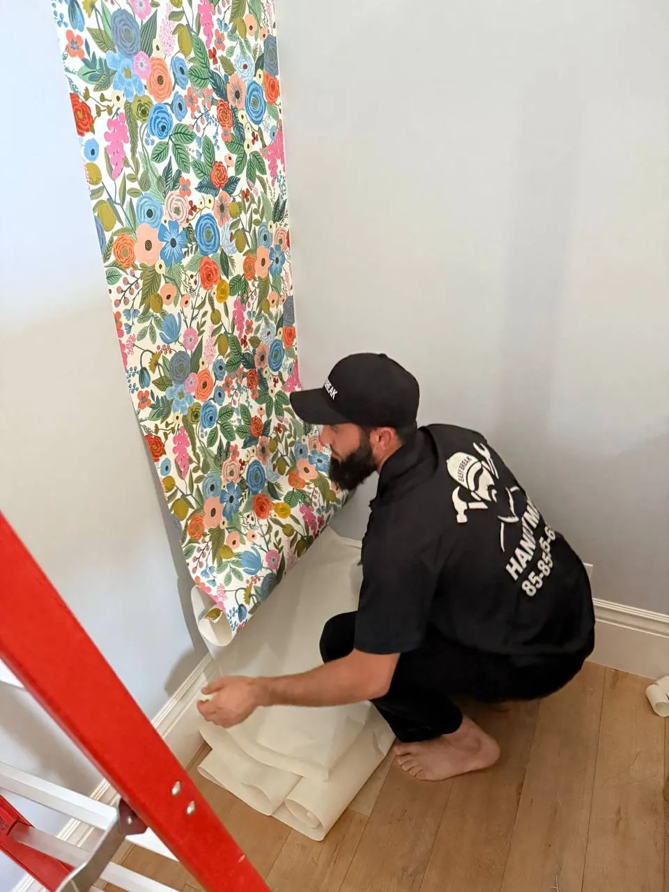 Handyman installing colorful mural wallpaper in a kids room